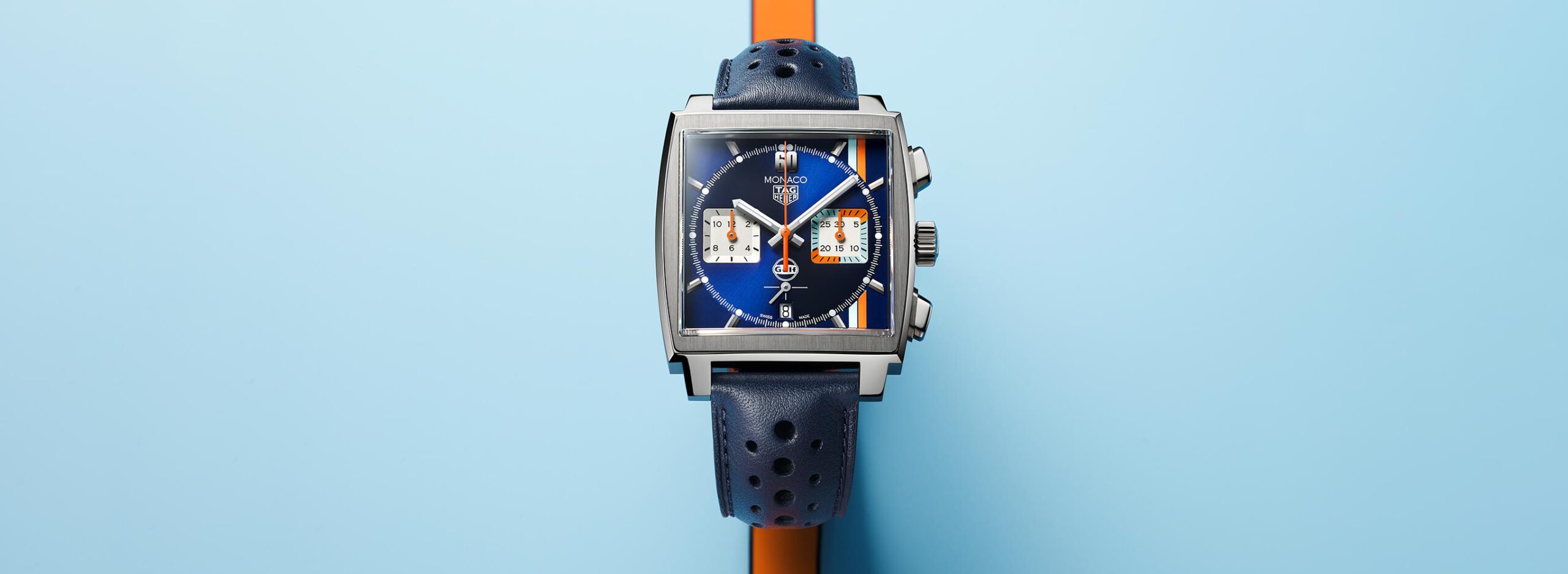 Uhrenikone TAG Heuer Monaco in der Gulf Edition vor einem hellblauen Hintergrund
